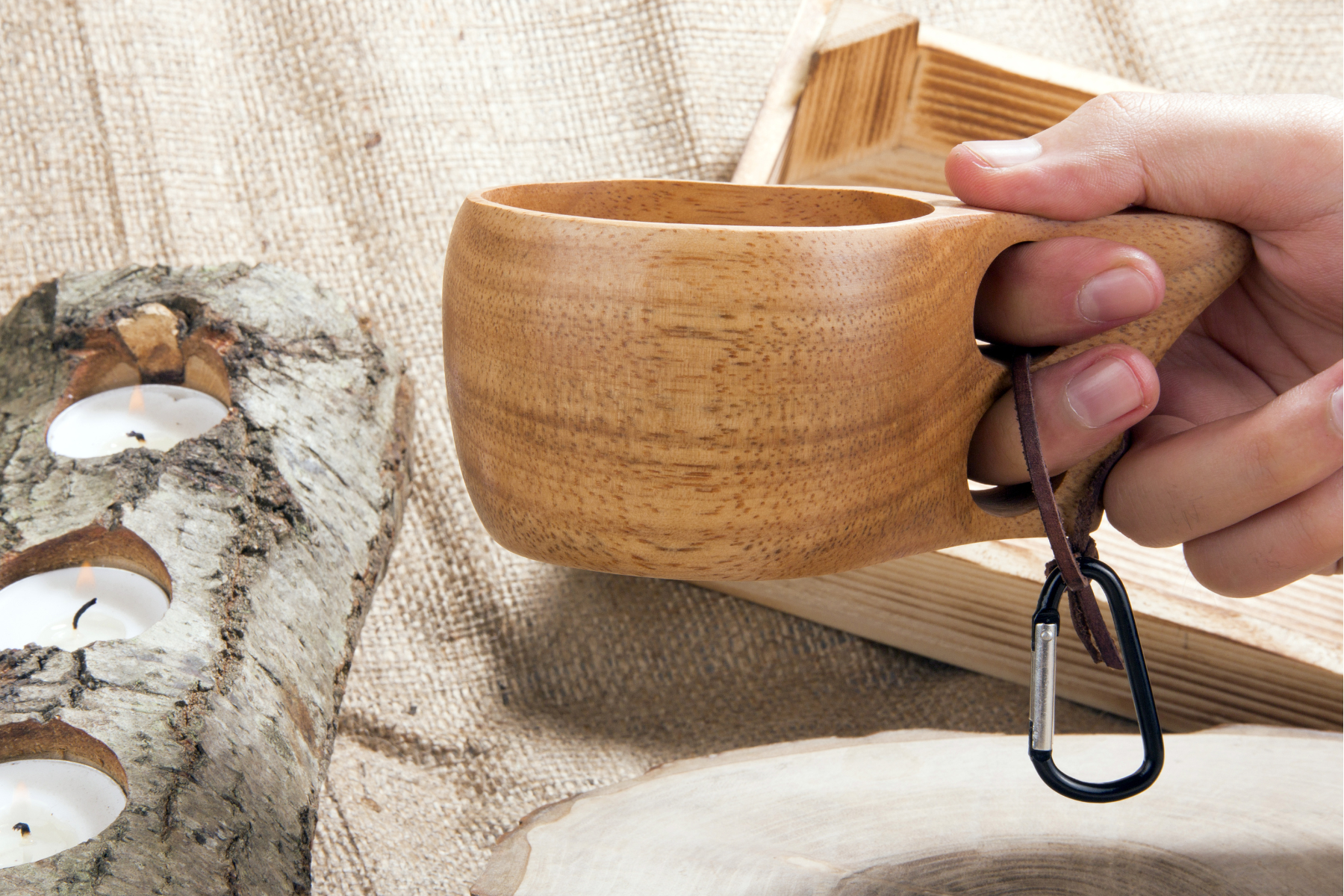 Photo of a wood carved kuksa cup being held in a person's right hand.